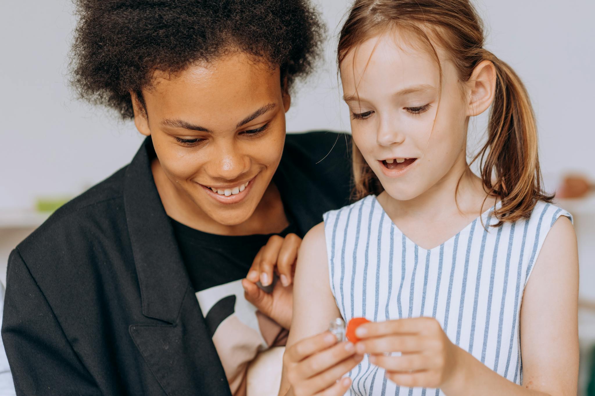 A joyful interaction between a teacher and child in a classroom setting, capturing genuine smiles.