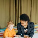 Educator and young girl collaborating on an educational activity in a vibrant classroom setting.