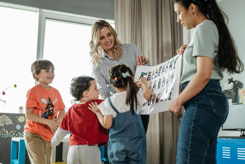 Preschool children and teachers enjoying an interactive alphabet learning session indoors.